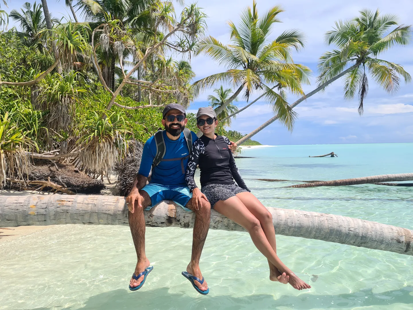 The two of us sitting on a leaning palm tree over turquoise water on an uninhabited island in the Maldives